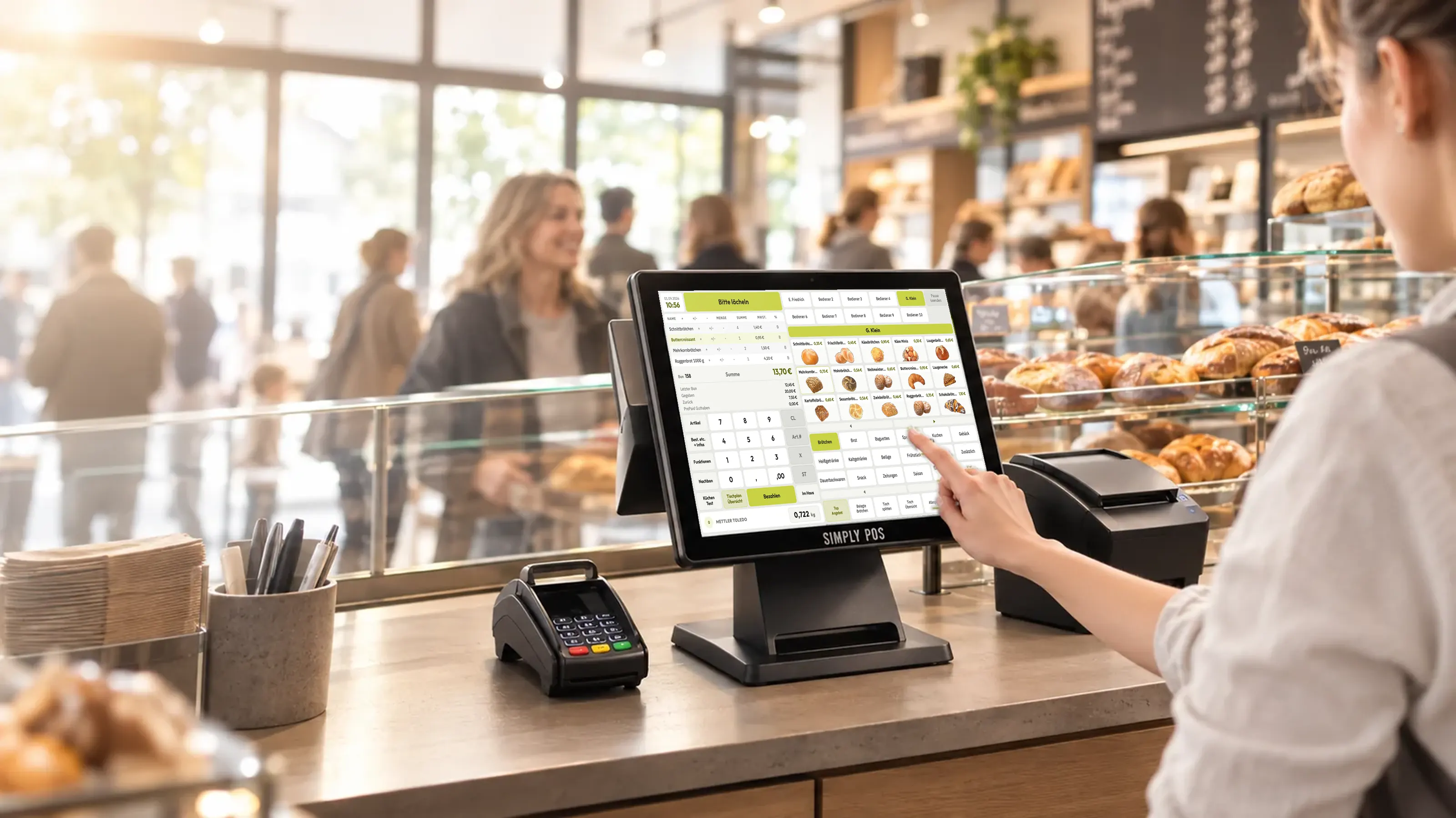 Simply&nbsp;POS Kassensystem im Einsatz an der Bäckertheke: Touchscreen-Kasse, Kartenterminal und Bondrucker, eine Mitarbeiterin bedient die Kasse